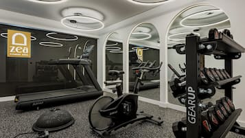 A modern fitness area with a treadmill, stationary bike, and weightlifting equipment.