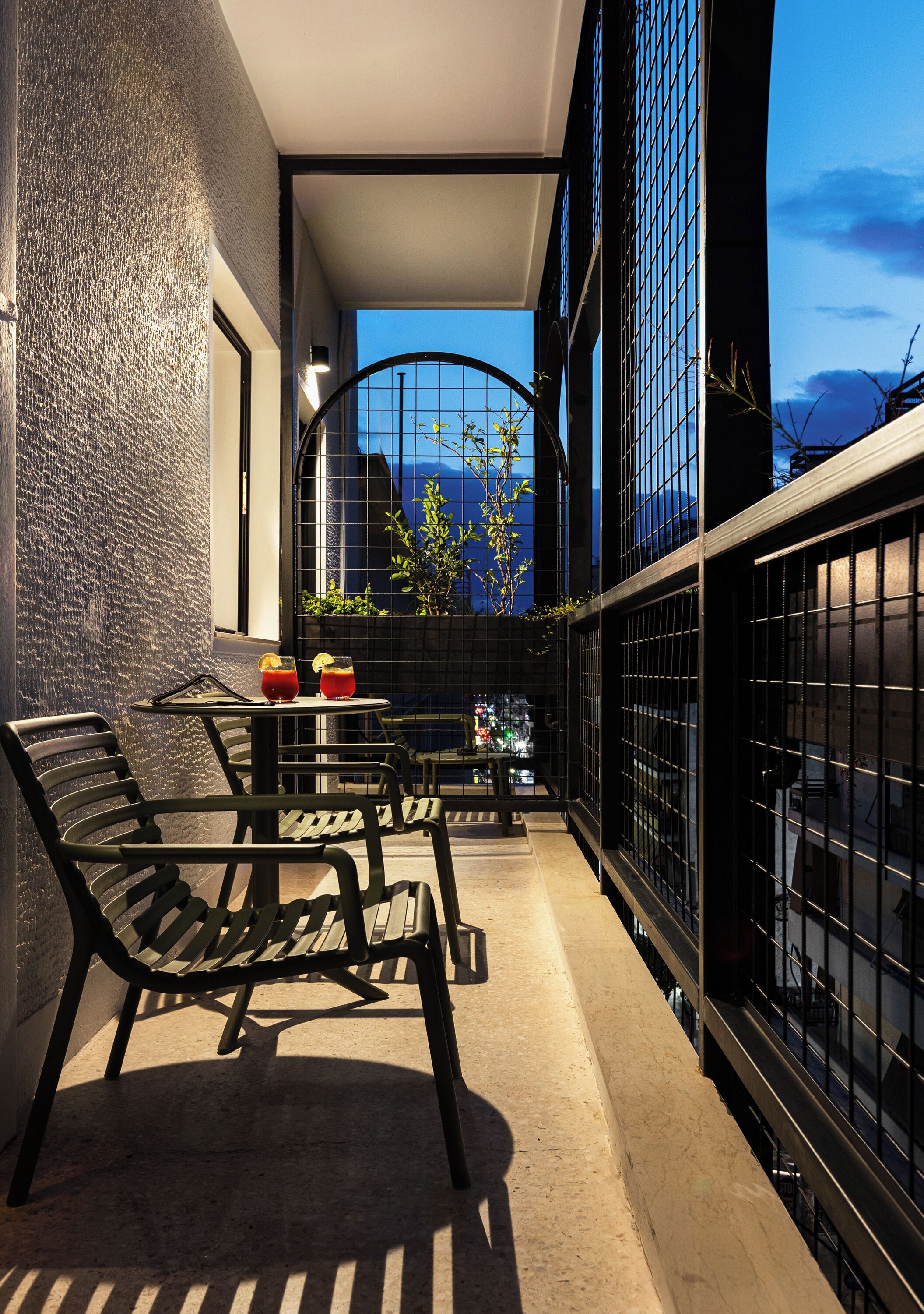 A balcony with outdoor seating, a view of the cityscape, and a railing.
