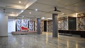 A spacious hall with a stage, a red sofa, and marble walls. - Hotel Taj Signature (Agra)