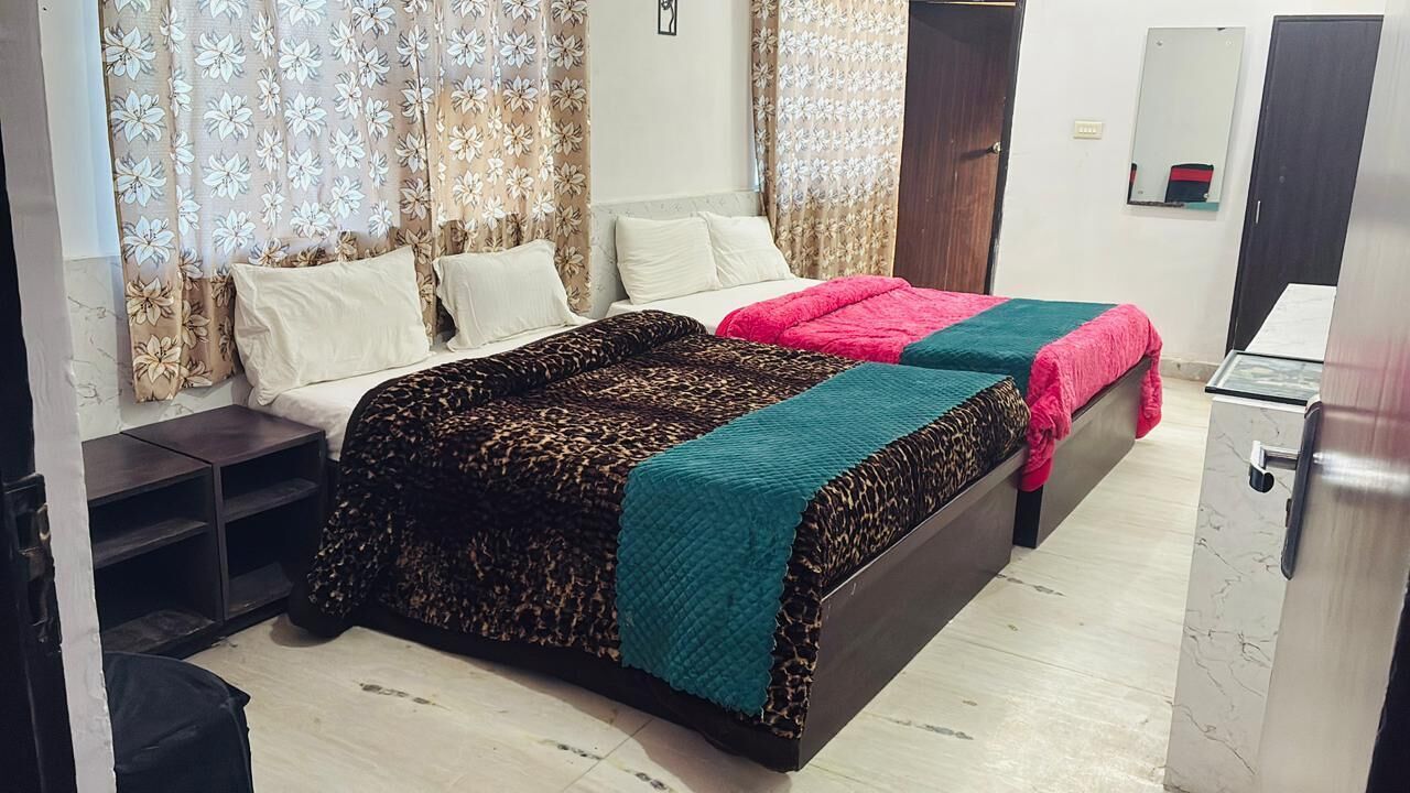 A bedroom with a double bed, a nightstand, a dresser, and floral curtains.