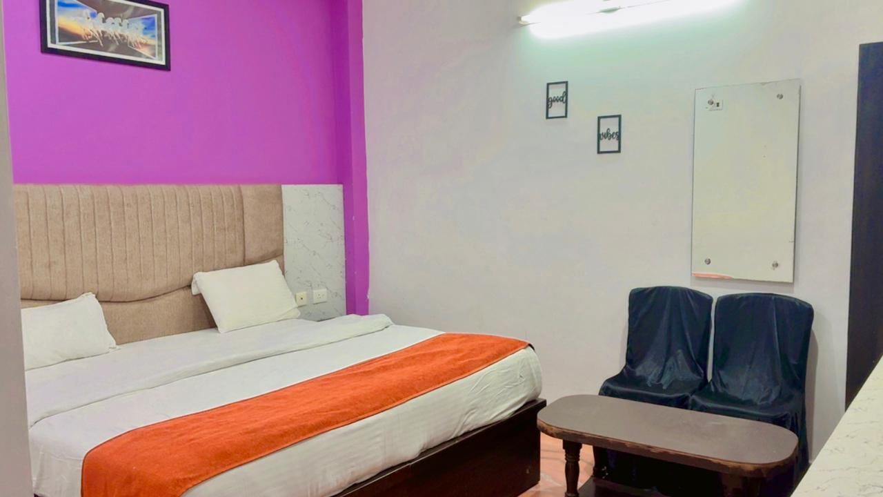 A hotel room with a bed, a small table, a chair, and a wall-mounted mirror.