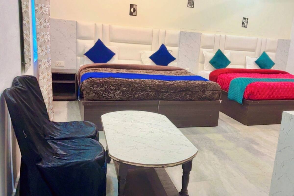 A hotel room with two beds, a small table, and a chair.