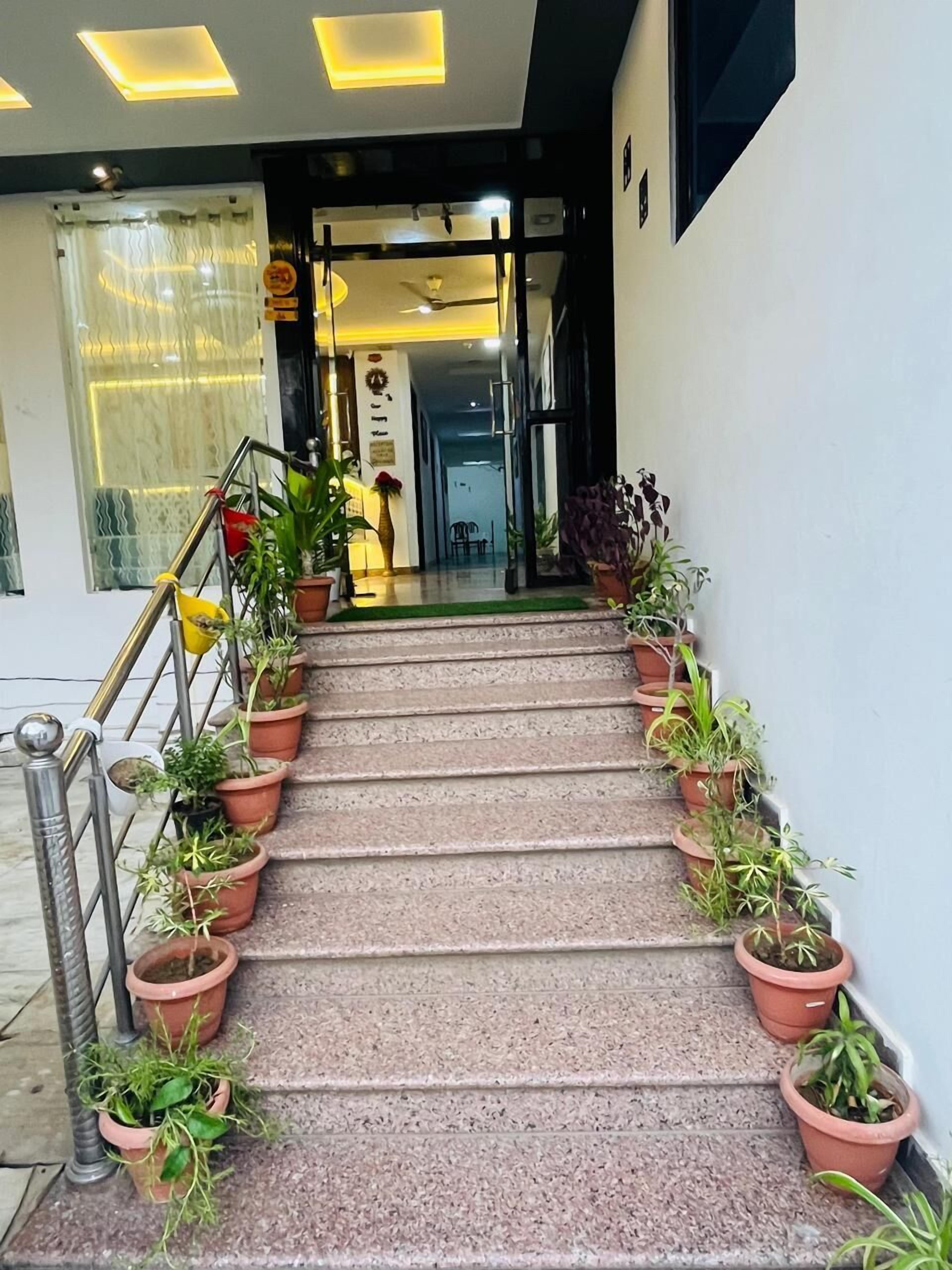 A staircase with potted plants on both sides, leading to a doorway with a sign above it.