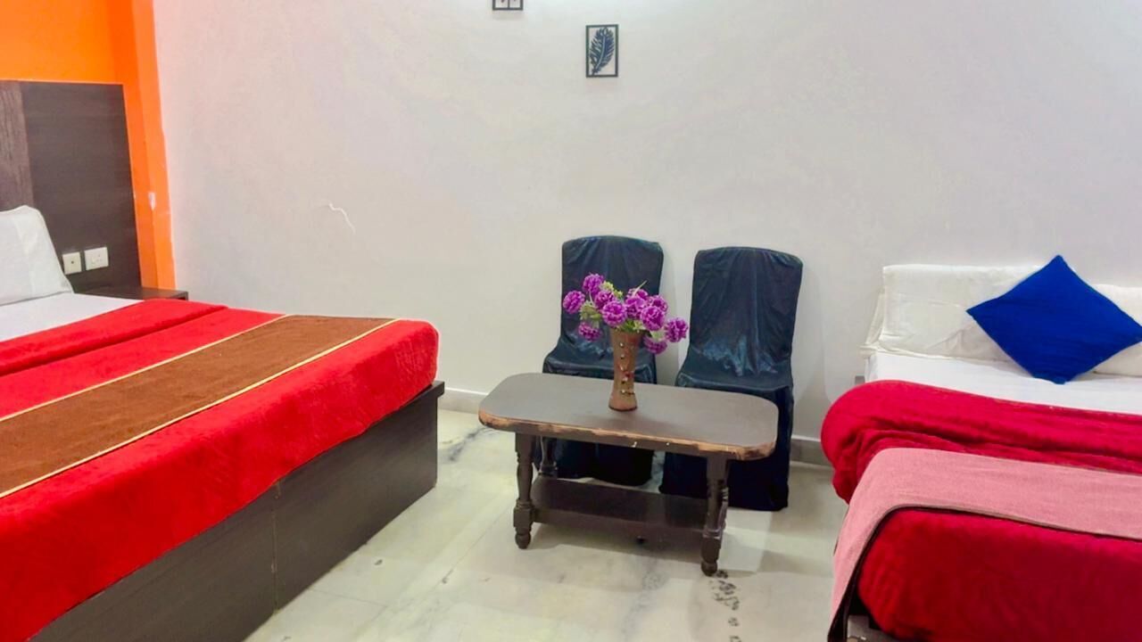 A hotel room with a bed, a small table with a vase of flowers, and two chairs.