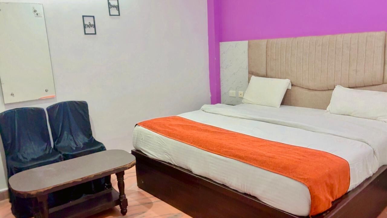 Una camera d'albergo con un letto, un tavolino e due sedie.