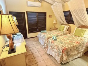 A room with two beds, a desk with a lamp, and a window with shutters. - Relax & Recharge in Meridian – 2BR Home w/ Private Pool (St John)