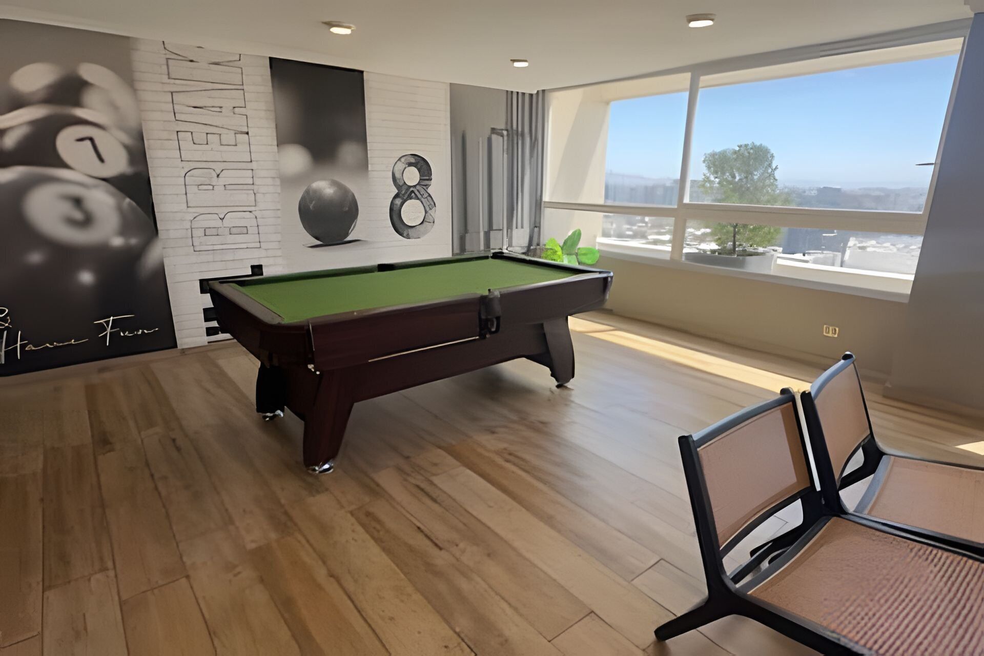 Una mesa de billar en una habitación con un ventanal grande, suelo de madera y una pared con un reloj y adornos.