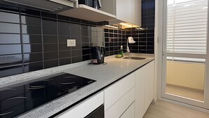Una cocina moderna con un salpicadero de azulejos negros, armarios blancos y una estufa negra.