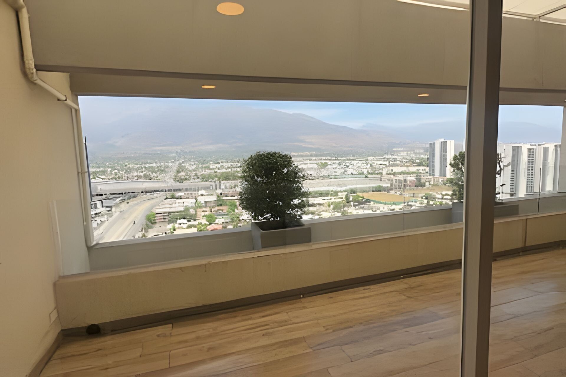 Quarto com uma grande janela dando para uma paisagem urbana com edifícios e uma montanha.