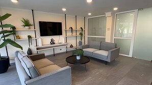 Una sala de estar moderna con un televisor de pantalla plana, sofás, una mesa de centro y plantas en macetas.