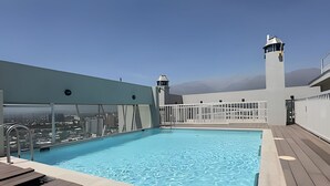 Una piscina en la azotea con vistas despejadas de la ciudad, una valla blanca y dos torres de vigilancia.
