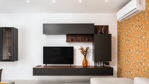 A modern living room with a flat-screen TV, built-in shelves, and a decorative vase. - Modern Stylish 3 BR APT with Balcony (Swieqi)