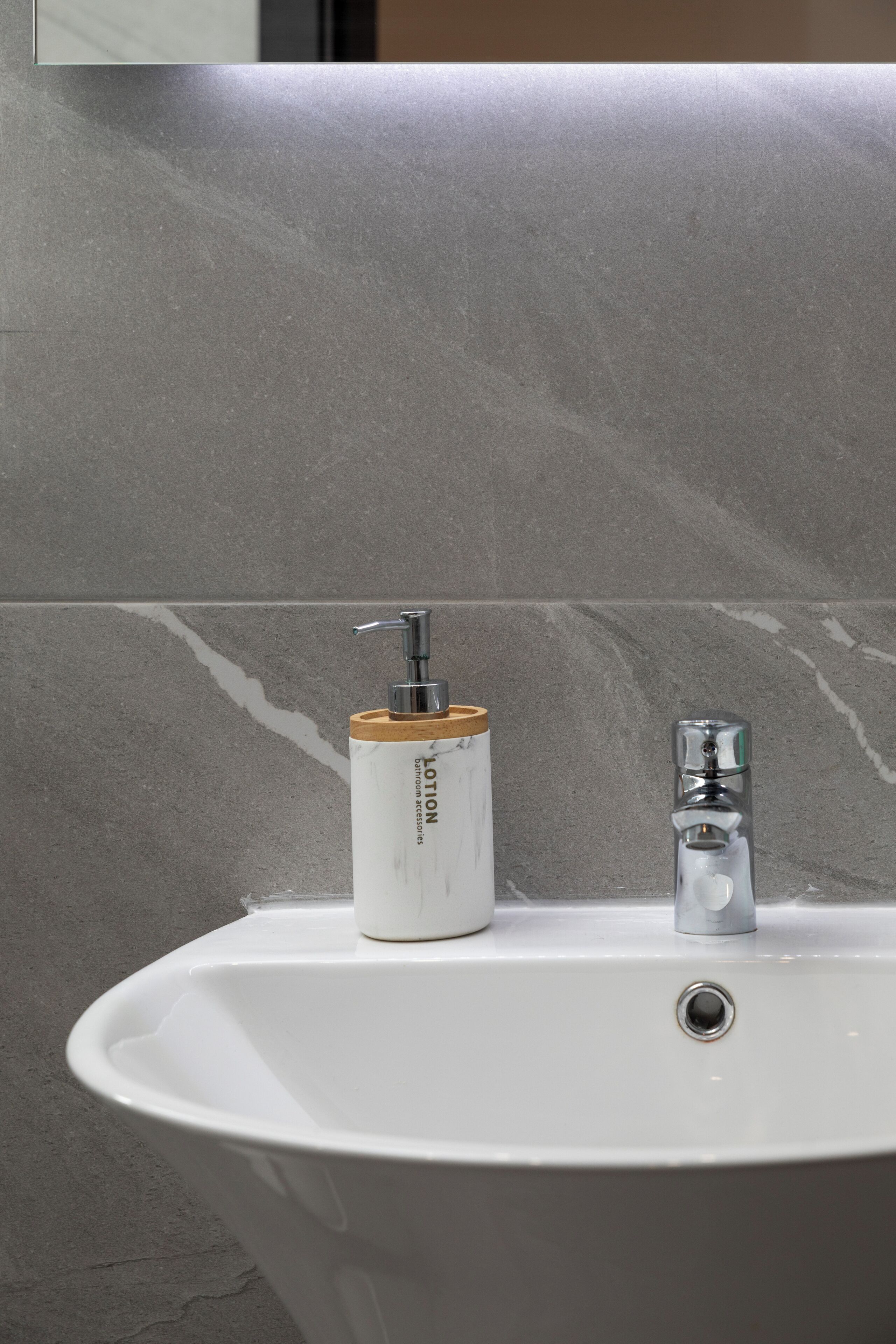 A bathroom sink with a bottle of lotion and a glass of water.