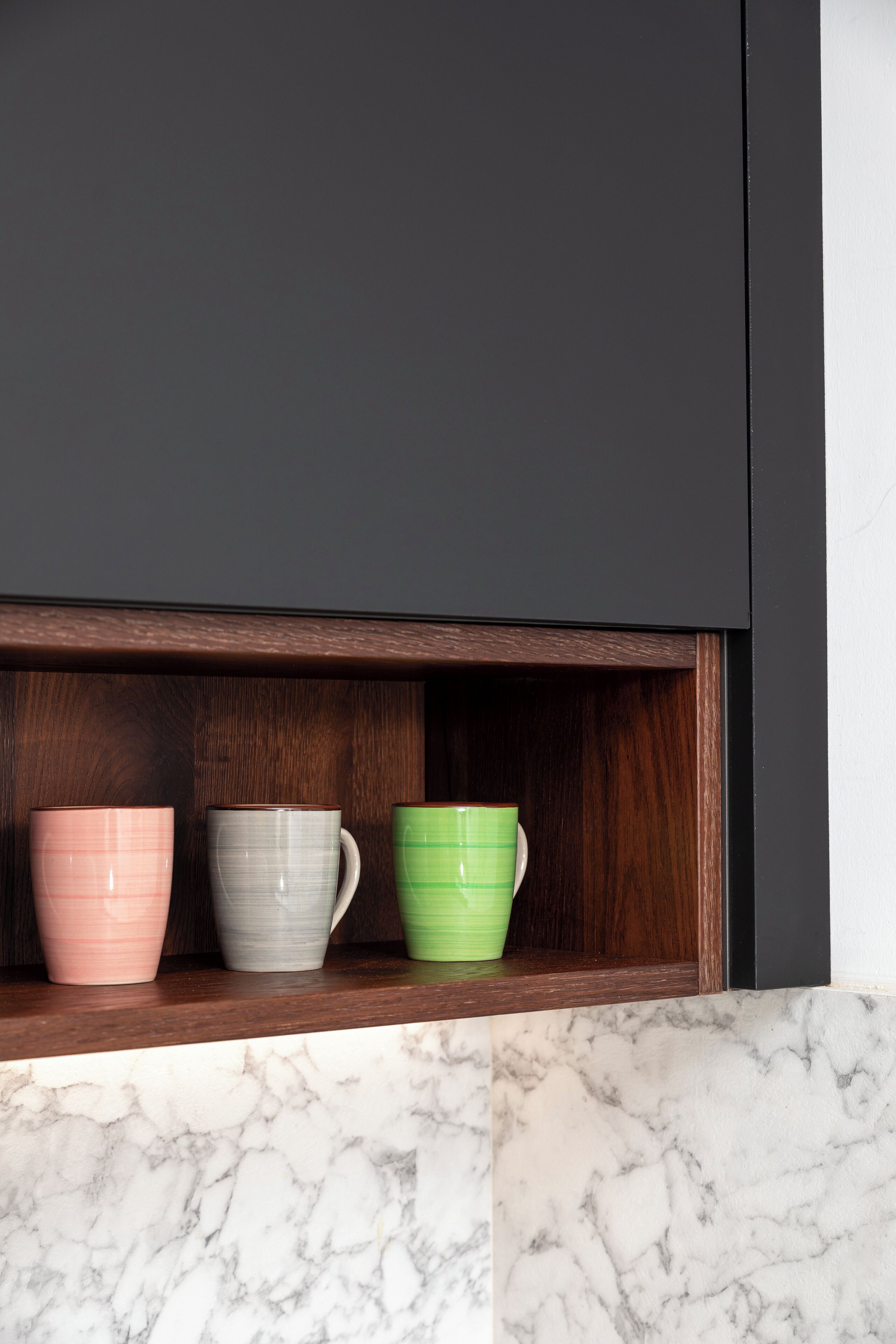 A shelf with three ceramic cups in different colors.
