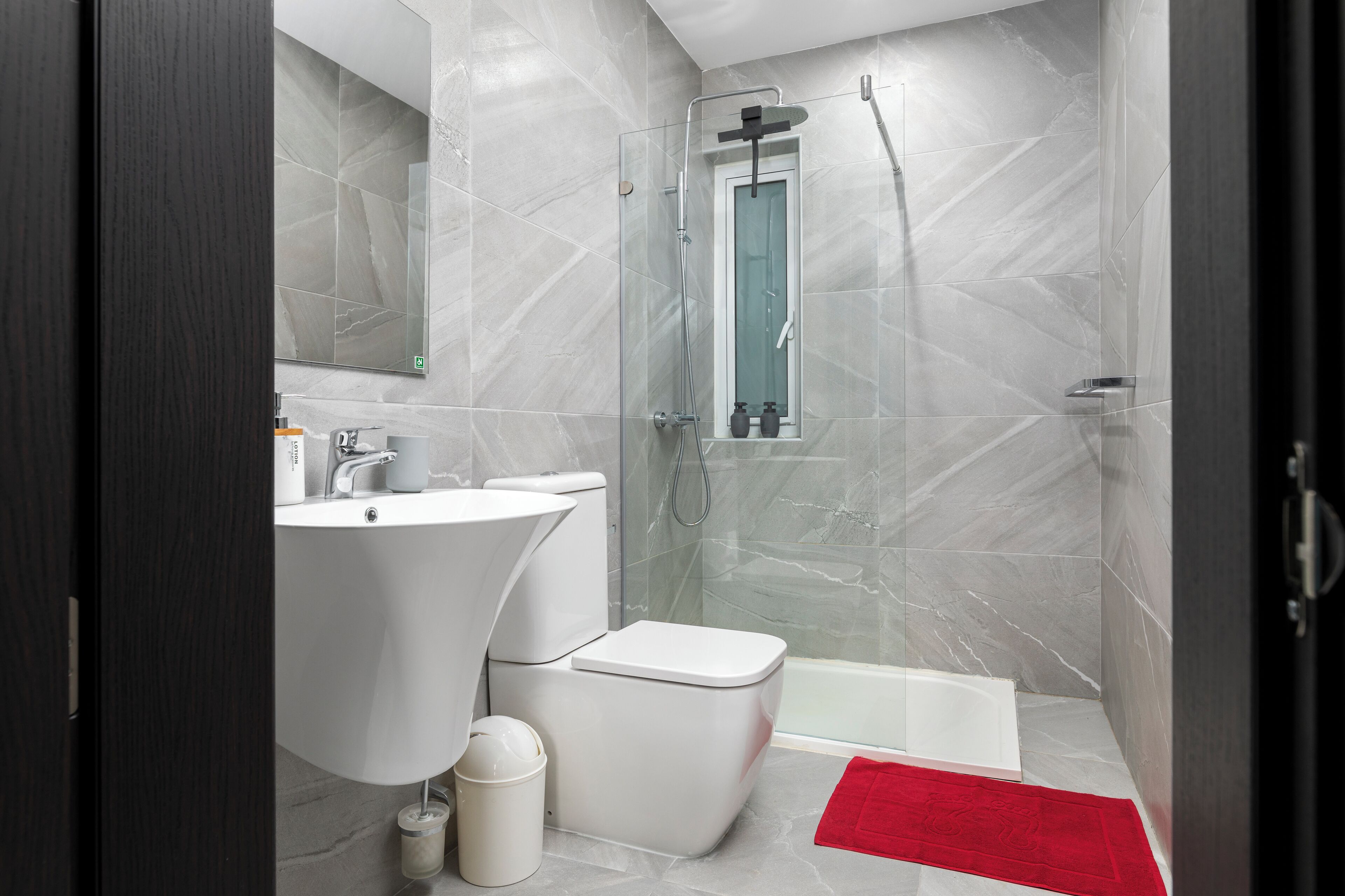 A modern bathroom with a glass-enclosed shower, a white sink, and a toilet.