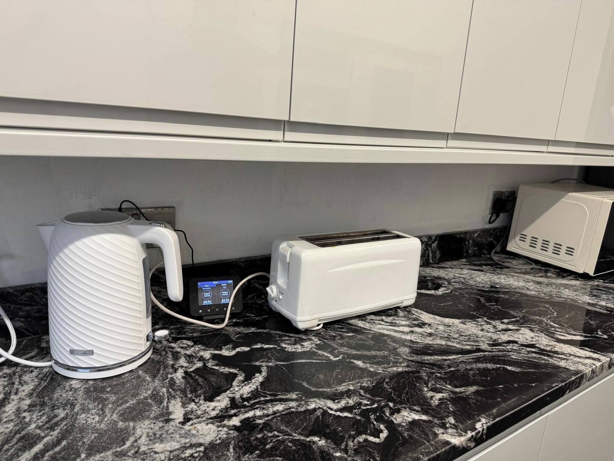 A kitchen with a marble countertop, a kettle, a toaster, and a microwave.
