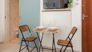 A small dining area with two chairs, a table, a TV mounted on the wall, and a door. - 5 Minutes From Copacabana Beach Bi202 (Rio de Janeiro)