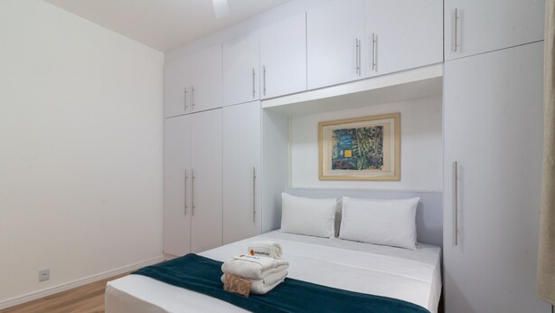 A bedroom with a bed, white wardrobe, and a painting on the wall. - 4 Minutes From Leblon Beach Ga207 (Rio de Janeiro)