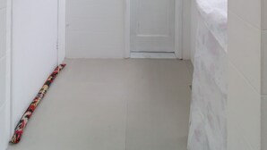 A narrow hallway with a white door at the end, a towel hanging on the right wall, and a patterned object on the floor. - 4 Minutes From Leblon Beach Ga207 (Rio de Janeiro)