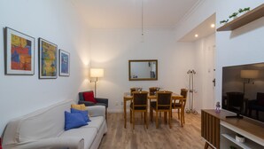 A living room with a sofa, a dining table with chairs, a TV, and framed artwork on the wall. - 4 Minutes From Leblon Beach Ga207 (Rio de Janeiro)