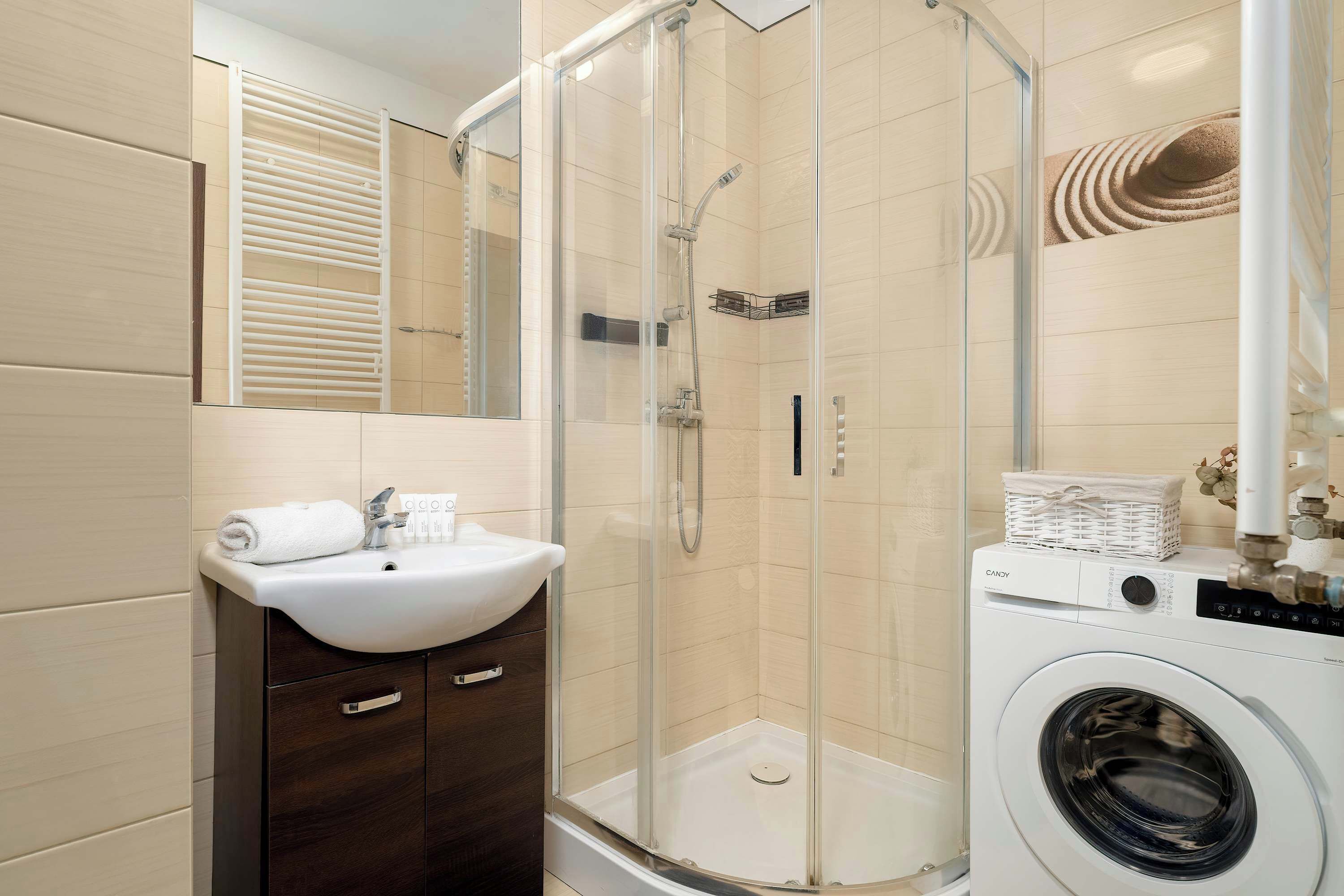 Une salle de bain avec une douche à parois de verre, un lavabo, un miroir et un lave-linge.