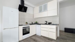 Una cucina moderna con mobili bianchi, forno integrato, lavastoviglie e microonde nero.