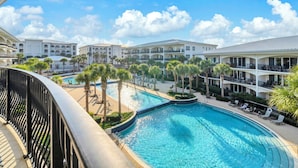 Resort com uma piscina grande, várias varandas e palmeiras.