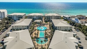 Um resort com vários edifícios, uma piscina central e vista para o oceano.