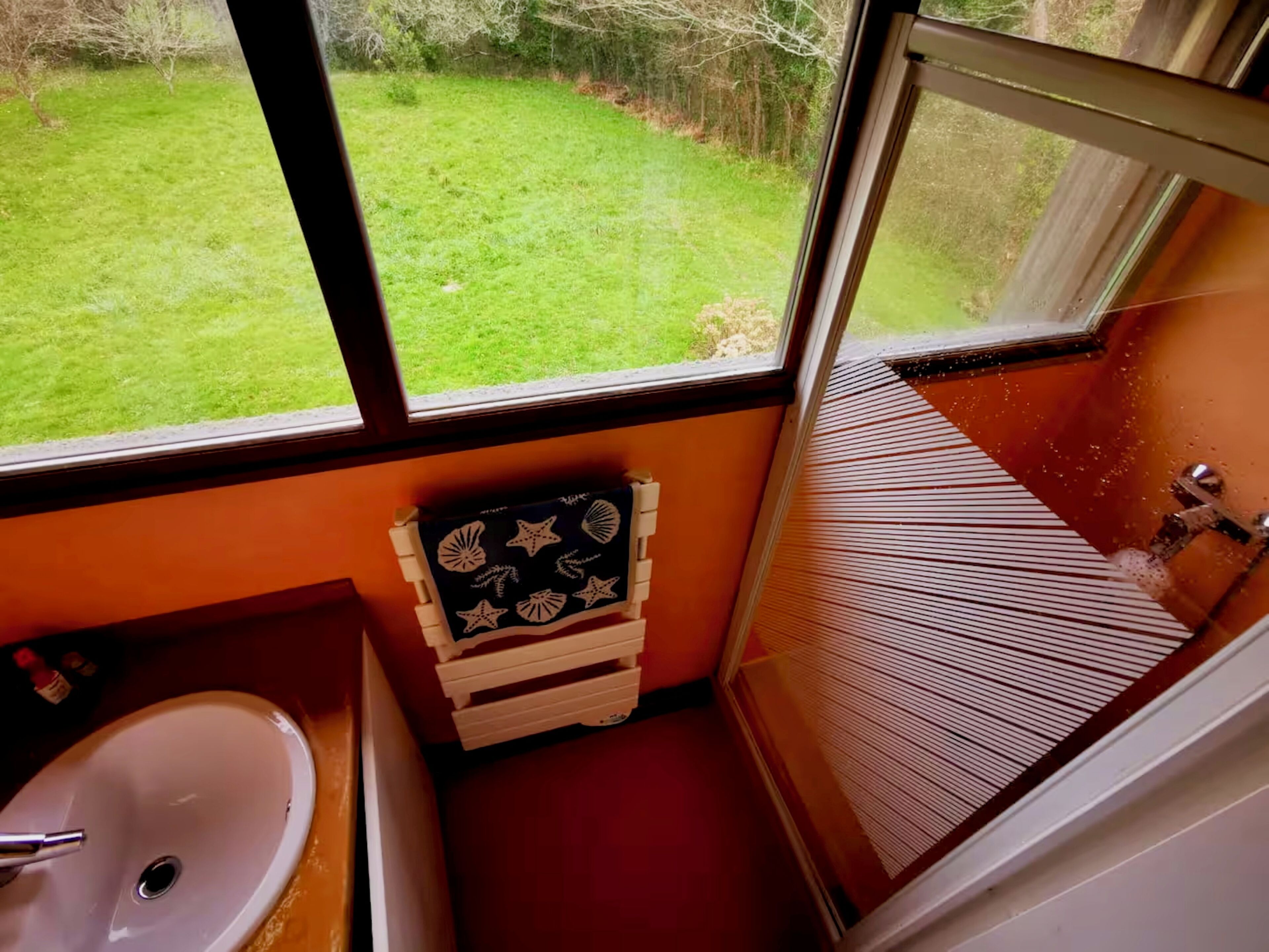 A bathroom with a window, a sink, and a small wooden chest.