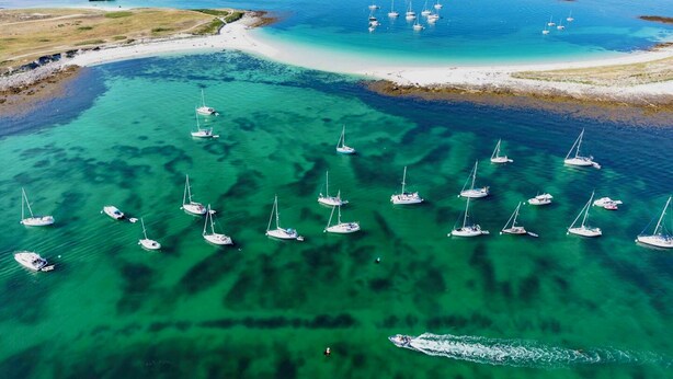 Eine Luftaufnahme einer Küstenregion mit zahlreichen Segelbooten in klarem, türkisblauem Wasser.