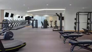 Une salle de sport équipée de tapis de course, d’appareils de musculation et de tapis de sol pour les exercices.