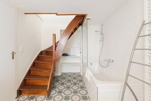 Baño con escalera de madera, ducha y baldosas de suelo con diseño.