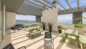 A rooftop terrace with a view of the city, featuring outdoor seating and potted plants. - Oceana Suites Cerro Placeres (Valparaiso)