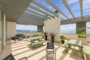 A rooftop terrace with a view of the city, featuring outdoor seating and potted plants. - Oceana Suites Cerro Placeres (Valparaiso)