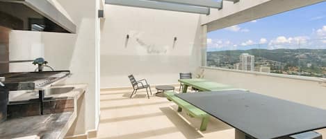 An outdoor patio area with a grill, seating, and a view of the cityscape.