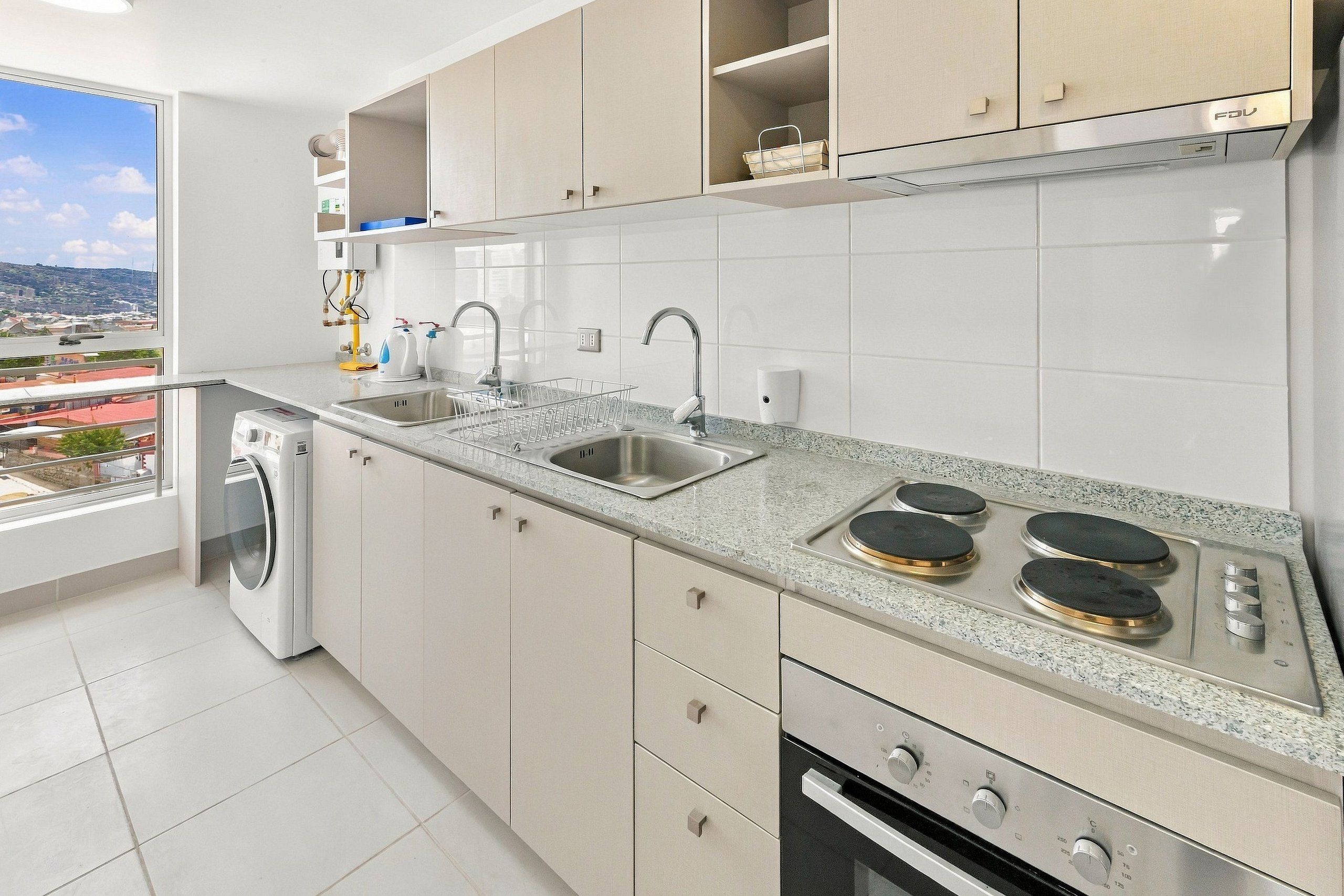 A modern kitchen with a built-in washer, double sink, and a stove with four burners.