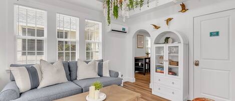 A modern living room with a grey sofa, wooden coffee table, and white walls.