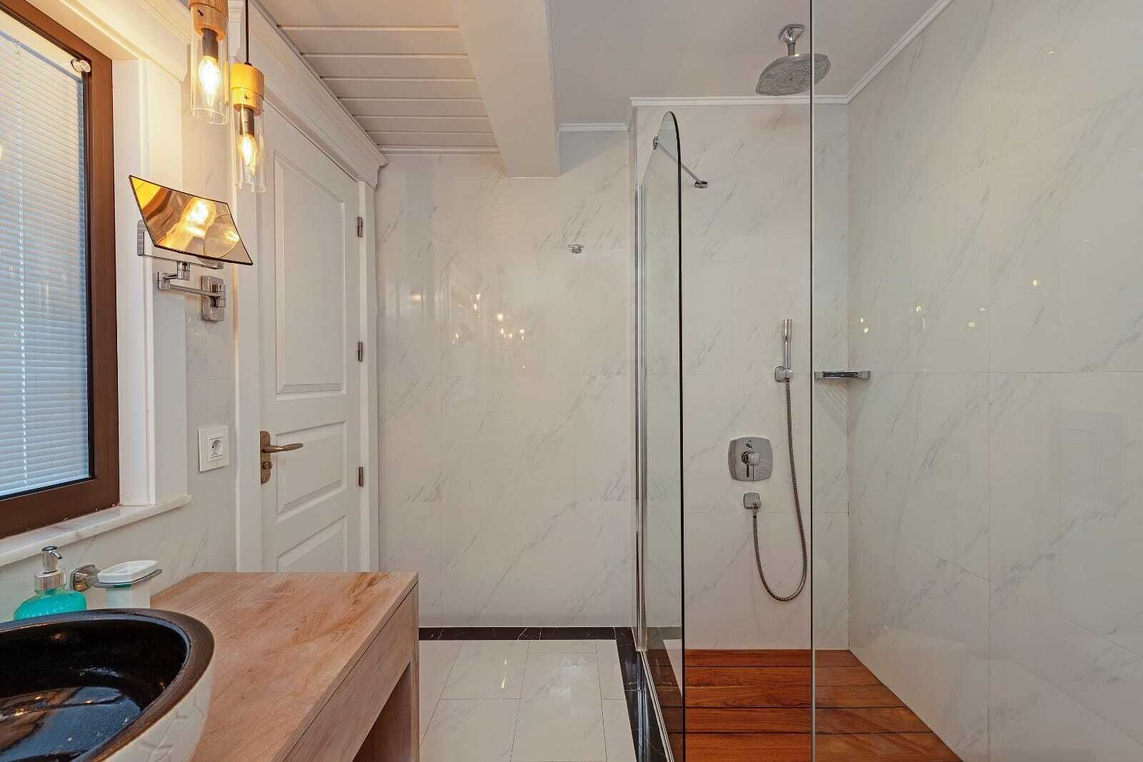 Une salle de bain moderne avec une douche à parois de verre, un meuble-lavabo en bois et un sol carrelé en marbre.