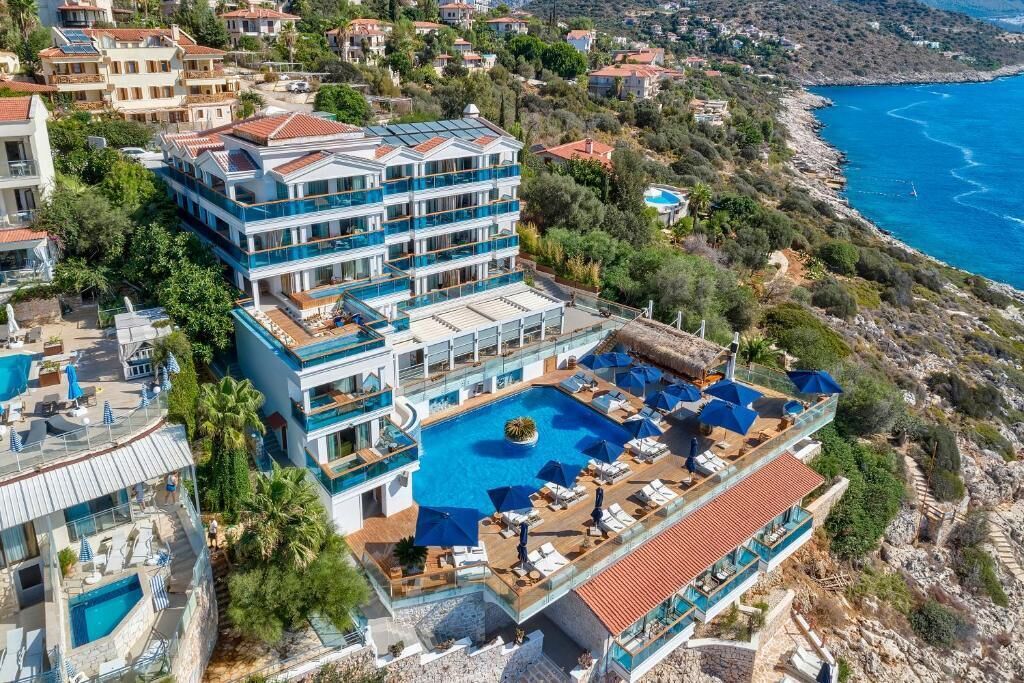 Un hotel de varios pisos con piscina en la azotea y balcones con vistas a la costa.