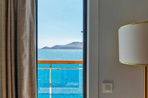 Een kamer met een groot raam dat uitzicht biedt op de zee en verre bergen.