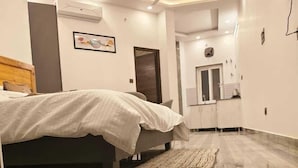 Un dormitorio moderno con cama, ventilador de techo y vista a la cocina.