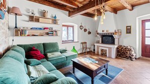 Un accogliente soggiorno con un divano verde, travi in legno, un camino e una libreria.