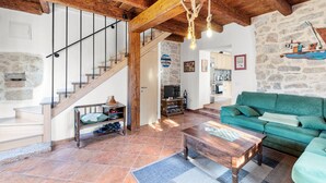 Un'ampia zona giorno con una scala in legno, un divano verde e un tavolino da caffè.