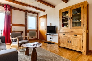 Un salon avec un téléviseur, un meuble en bois et un rideau rouge.