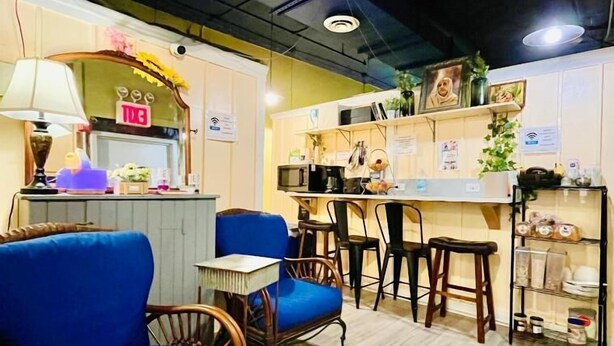 A cozy seating area with blue upholstered chairs and a wooden table, a counter with a sign reading "EXIT", and shelves with various items. - New York Spirit Retreats HOSTEL (New York)