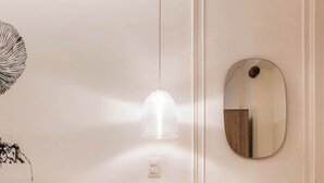 Ein Schlafzimmer mit Bett, Nachttisch, Wandspiegel und Pendelleuchte.