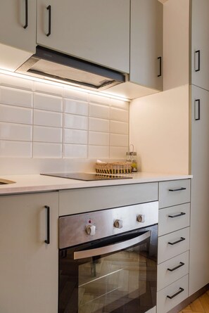 A kitchen with white cabinets, a stainless steel oven, and a range hood. - Elegant Studio | AC and Patio Perfect for Families (Providencia)