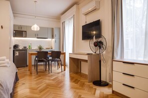 Eine moderne Küche mit Mikrowelle, Herd und Spüle. Ein Essbereich mit Tisch und Stühlen ist vorhanden. Ein Ventilator steht in der Nähe eines Fensters.