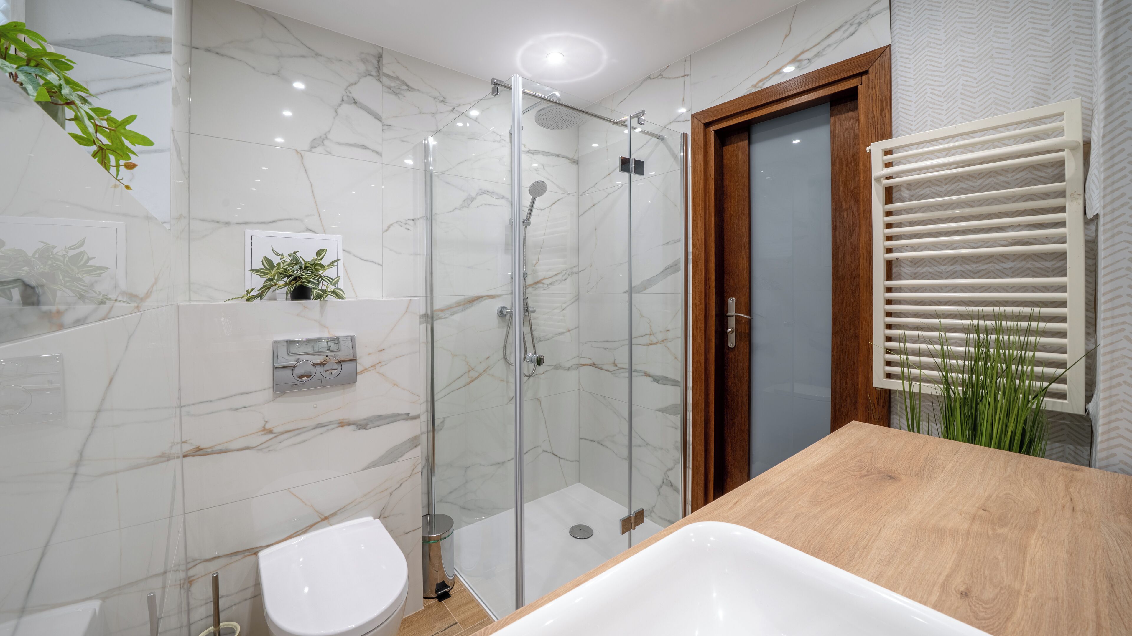 A modern bathroom with a glass-enclosed shower, a wooden vanity, and a toilet.