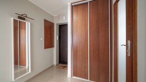 Un couloir avec des portes en bois, un mur blanc et un sol carrelé.